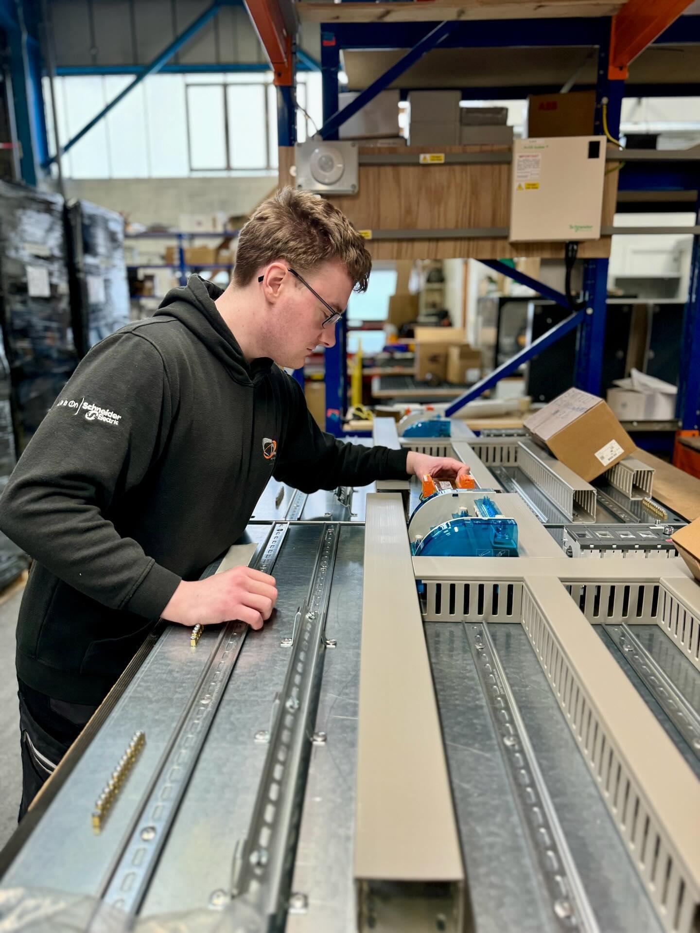 A technician installing trunking on a panel
